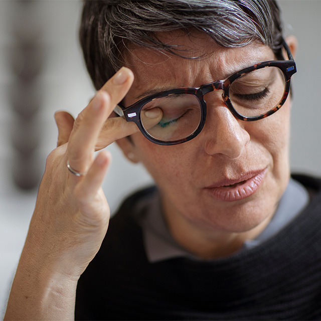 woman in glasses rubbing eye